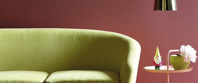 Ambiance Little Greene : canapé vert devant un mur rouge